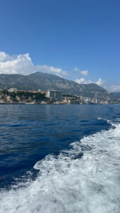 Panoramic view of Monaco’s coastline, mountains, and cityscape from boat during daytime.