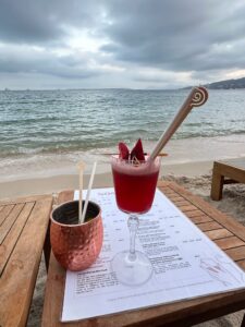 Cold berry cocktail on beachside table with ocean view and overcast sky in Antibes, France.