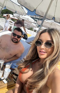 Sunny outdoor poolside leisure scene with women sunbathing and relaxing under umbrellas in Cannes, France.