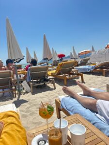 Relaxing beach lounge chairs by the ocean under umbrellas on sunny day in Cannes, France.
