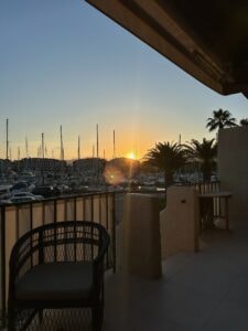 Spectacular sunset view over Marina with yachts and palm trees at twilight in Saint Tropez, France.