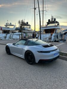 Luxury Porsche 911 Cabriolet near yachts at marina, sunset view, stylish sports car, boat dock, coastal luxury in Saint Tropez, France.