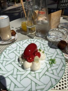 Fresh berry dessert with whipped cream and icing on a stylish green geometric plate at outdoor Dior Restaurant café in Saint Tropez, France.