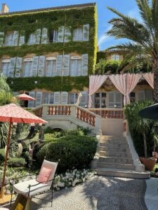 Violet ivy-covered hotel with pink canopy and lush garden of the Dior Restaurant Saint Tropez, France