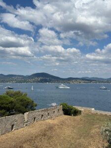 Boats sailing on a calm lake with hills in the background under partly cloudy sky in Saint Tropez, France.