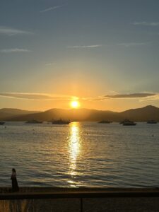 Stunning sunset over the harbor with yachts and mountain scenery, perfect for travel and vacation photography.