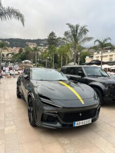 Luxury sports car in Monte Carlo, Monaco with scenic hillside and palm trees.