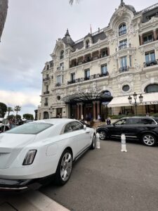 Luxury Hotel de Paris in Monte Carlo with classic architecture and luxury cars parked outside.