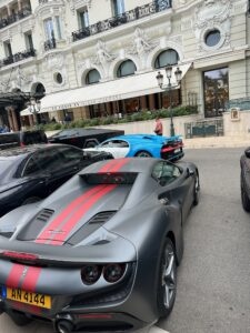 Luxury sports cars parked in front of an upscale hotel in Monaco.