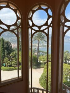 Vibrant landscape view of palm trees, lush greenery, and a mountain backdrop through decorative windows.