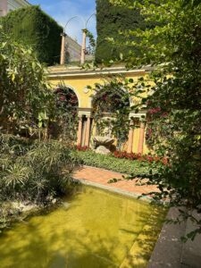 Colorful Mediterranean garden with a water fountain and lush greenery.