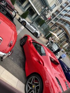 Luxurious Ferrari parked on a city street in Monaco with pedestrians and elegant surroundings.