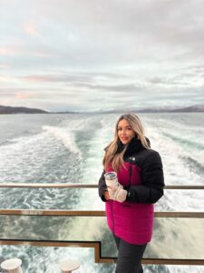 Woman on boat with scenic water view during daytime, holding coffee mug in Norway