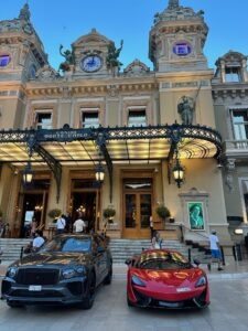 Luxurious Monte Carlo Casino in Monaco with high-end cars parked in front.