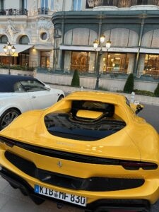 Luxury yellow Ferrari sports car in front of elegant boutique in Monaco.