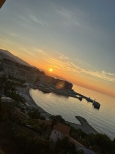 Sunset over a coastal city with harbor and mountains in the background, scenic ocean view, warm evening light, tranquil seaside landscape, vacation destination, Mediterranean coastline in Monaco.