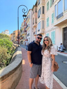 Elegant couple strolling in colorful European neighborhood with charming architecture and sunny weather in Monaco.