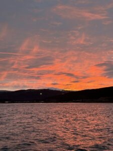 Vibrant sunrise over a calm body of water with silhouetted mountains in the background in Norway