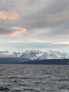 Snow-capped mountains over a dark ocean under a cloudy sky in a scenic landscape in Norway