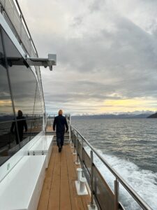 Seafarer walking on a boat deck with mountain view and cloudy sky in background in Norway
