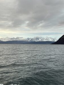 Snow-capped mountains reflected in the calm ocean with a cloudy sky, scenic nature landscape in fjord of Norway
