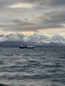 Snow-capped mountains and a boat on the ocean in a scenic coastal landscape in Norway