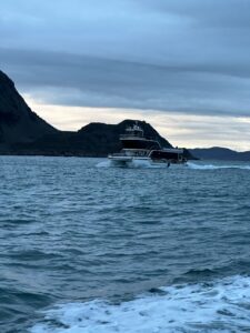 Luxury yacht sailing through scenic fjord with rugged mountains in the background in Norway
