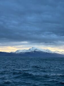 Snow-capped mountains and ocean under cloudy sky, scenic landscape of Northern Norway.