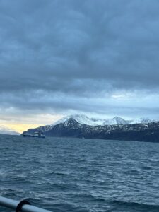 Snow-capped mountains and deep blue fjord with a boat, scenic coastal landscape in Norway.